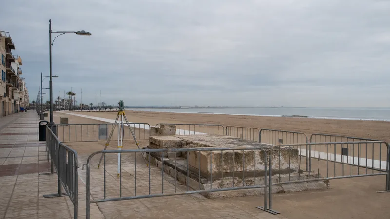 Base de piedra acotada y equipo topográfico en un paseo marítimo