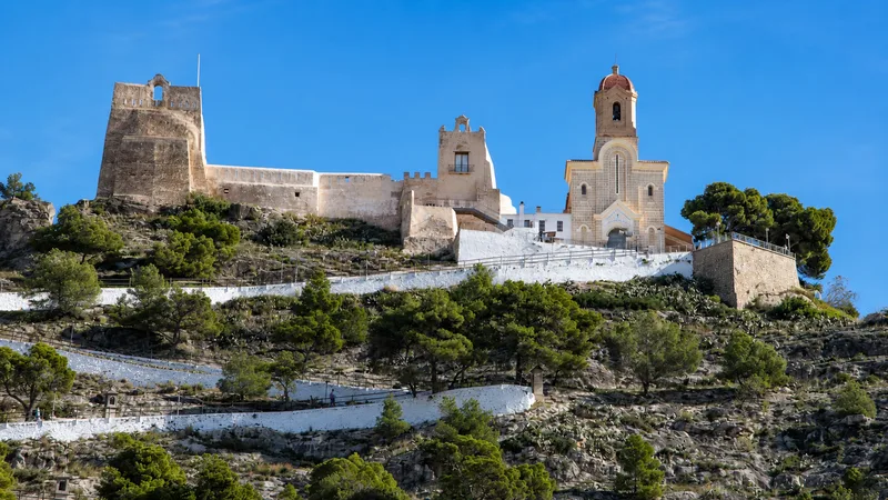 Castillo musulmán y Santuario de Cullera sobre la ladera con visitantes pequeños en el camino