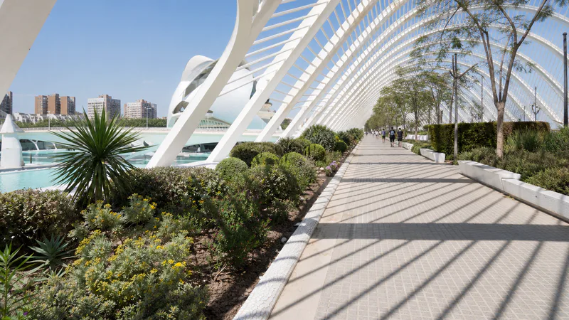 Paseo exterior ajardinado bajo los arcos blancos de l’Umbracle