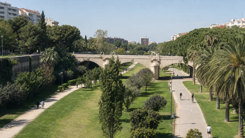 Tramo verde del antiguo cauce del Turia con senderos y un puente de piedra