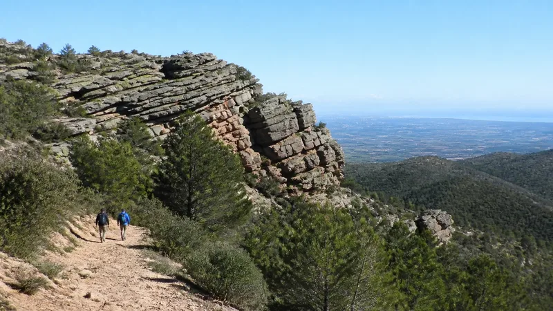 Excursionistas pequeños junto a grandes estratos de rodeno en la Serra Calderona