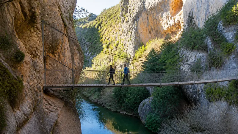 Primer puente colgante de Chulilla sobre el Turia con dos senderistas que muestran su escala