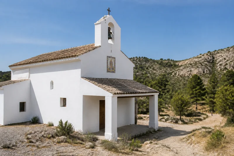Ermita encalada de Santa Bárbara de Chulilla con porche, espadaña y paisaje mediterráneo