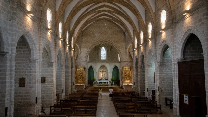 Nave gótica de piedra de la Colegiata de Gandia con visitantes pequeños ante el altar