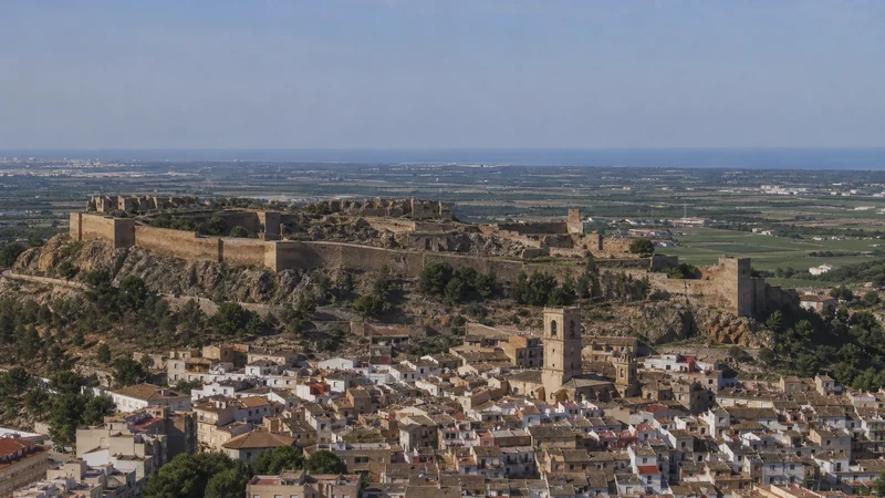Panorámica representativa del núcleo histórico de Sagunto bajo las murallas alargadas del castillo y con el Mediterráneo al fondo