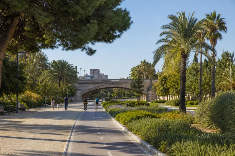 Senderos peatonales y ciclistas del Jardín del Turia bajo un puente histórico de piedra