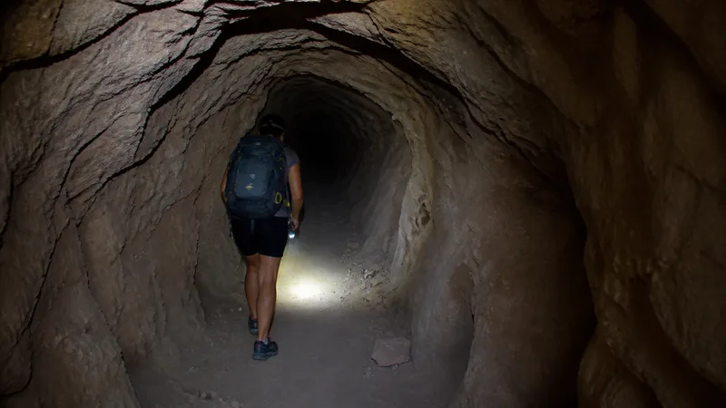 Excursionista con linterna dentro del largo y oscuro túnel de Olinches