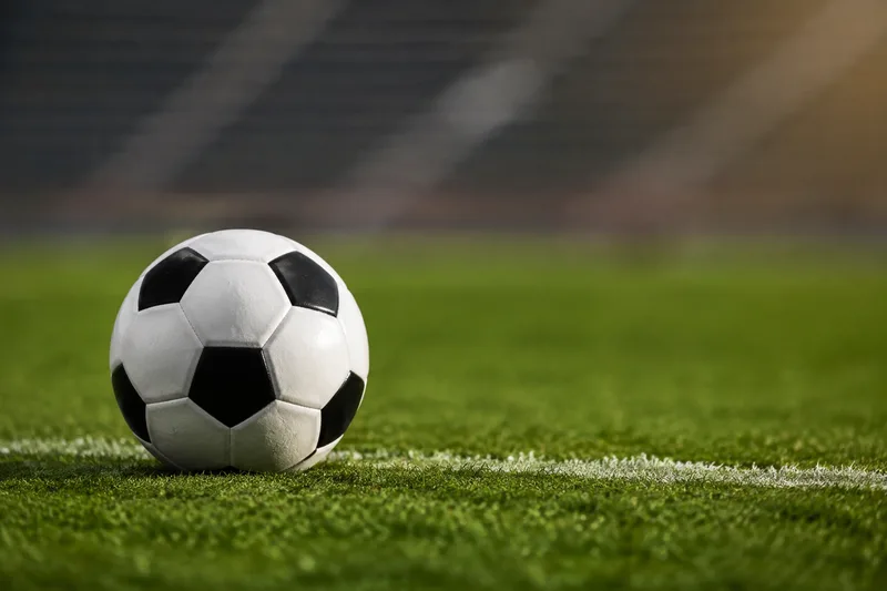 Balón de fútbol sobre el césped junto a una línea de cal