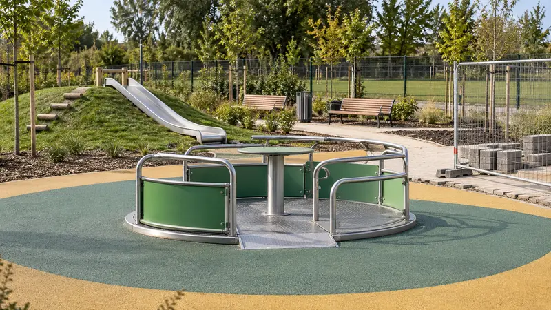 Carrusel infantil inclusivo a cota cero en un jardín en remodelación