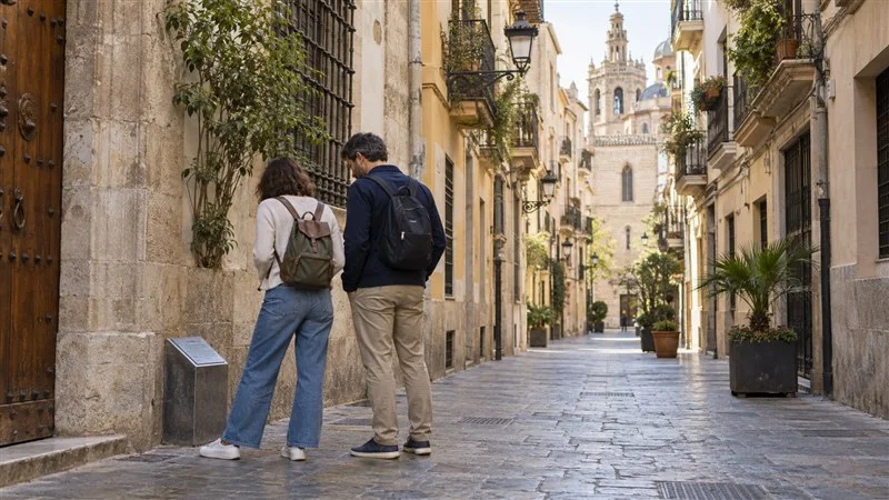 Dos personas observan una placa de ruta en una calle del centro histórico de València.